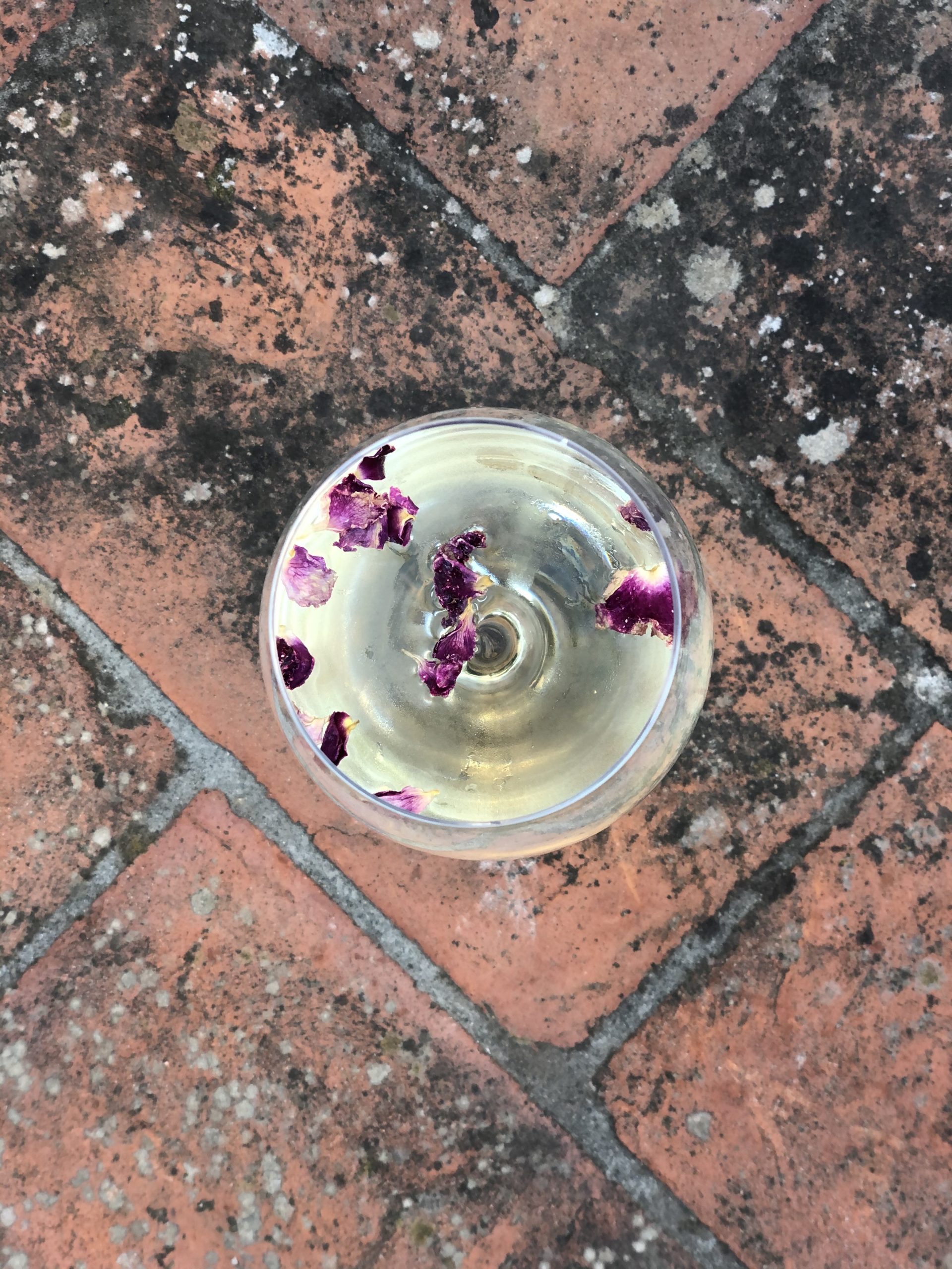 Glass of chilled white wine with rose petals